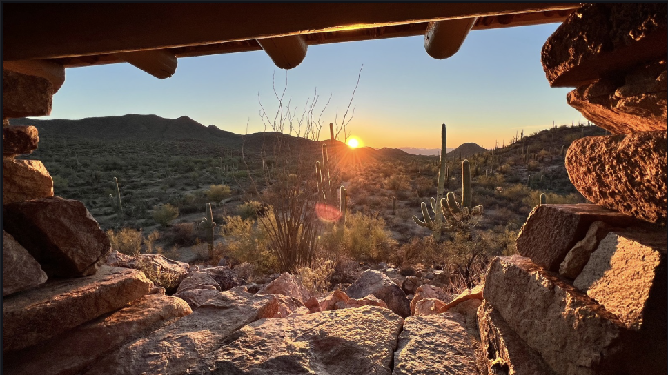 Desert sunset over cactus country, framed by stone walls